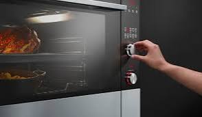 Built-in oven with control knobs and a roast cooking inside